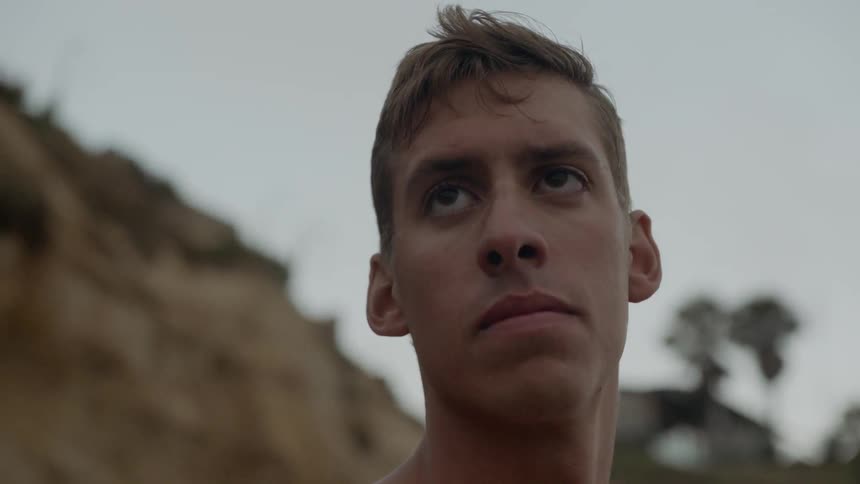 A shirtless man looking around while standing outdoors