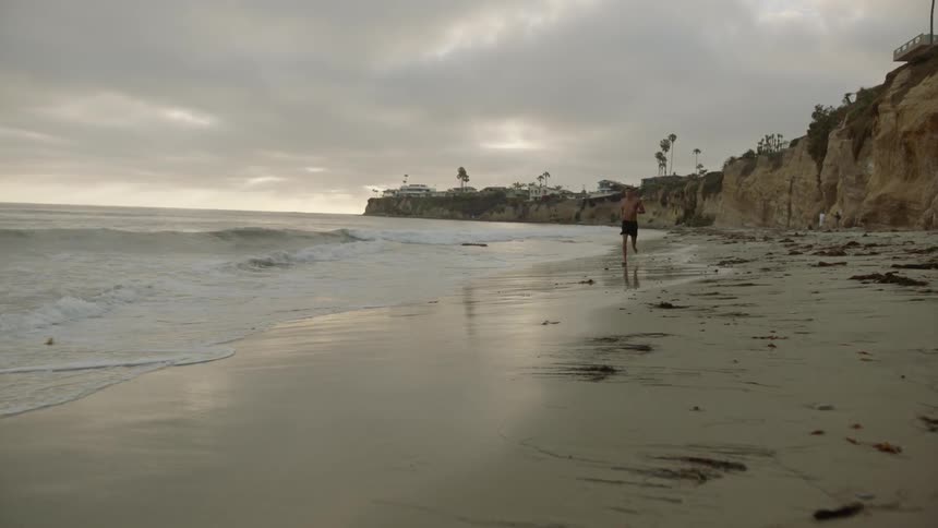 Man runs along the seashore on a cloudy day