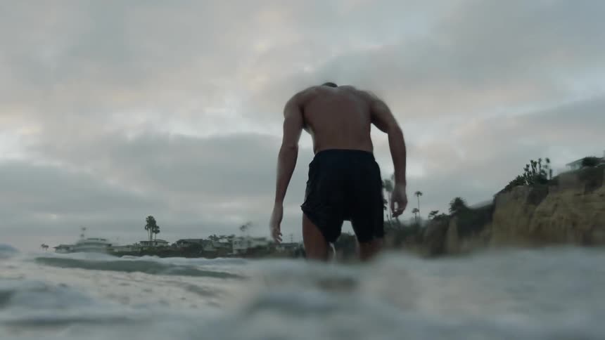 A man standing on the beach getting wet by the waves