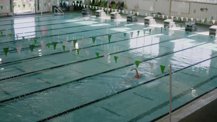 A woman swims in a lane of a large indoor pool