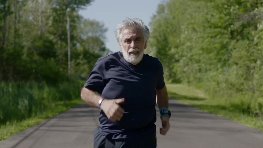 An elderly man runs down a road