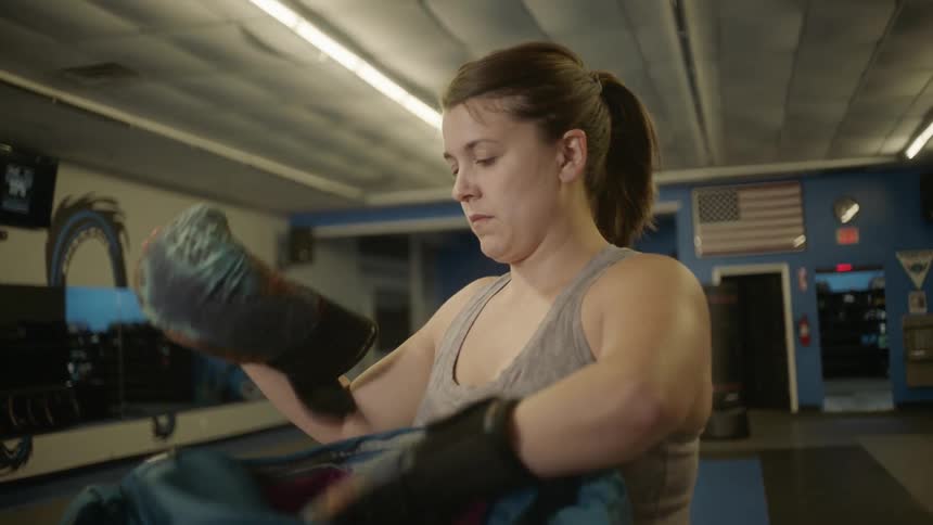 Woman wears boxing gloves in a gym