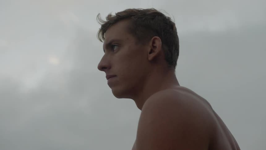 A shirtless man contemplating