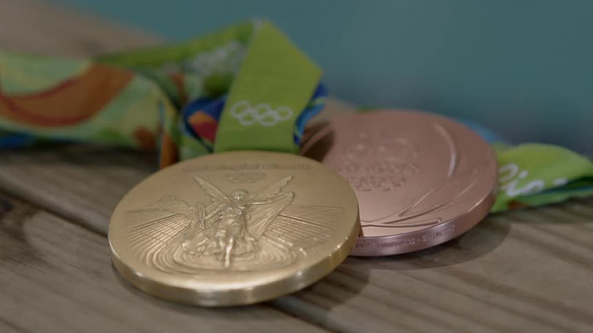 An olympic gold and bronze medal sitting on a table