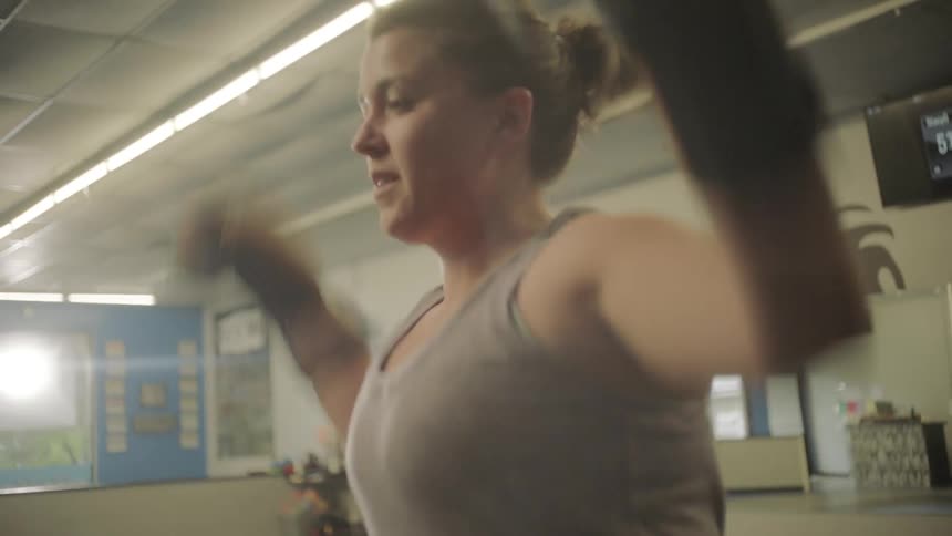 Blonde woman wearing gloves trains in a gym
