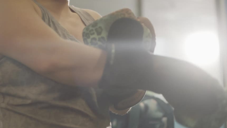 A woman puts punching gloves on