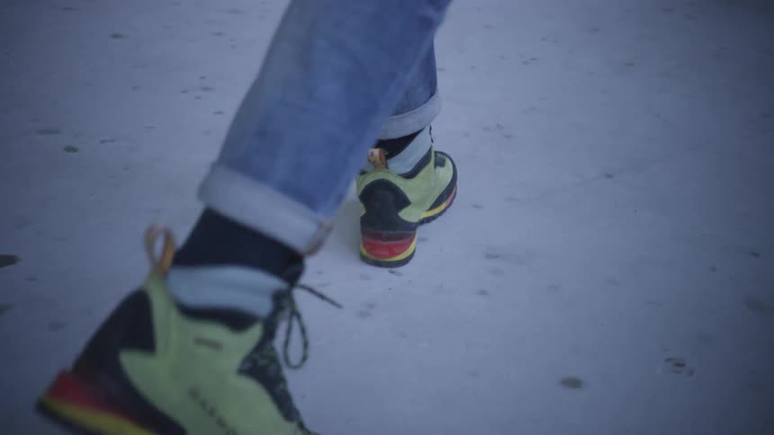 A man wearing high top gym shoes walks across the floor