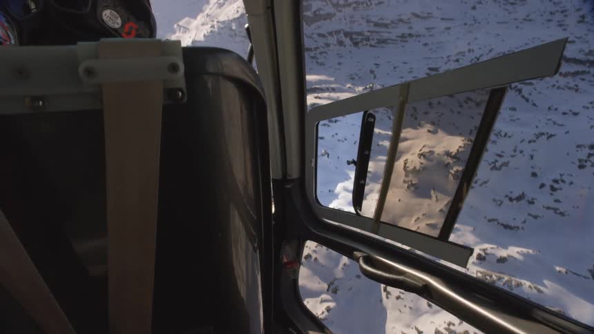 A person is flying a helicopter over the snow covered hills