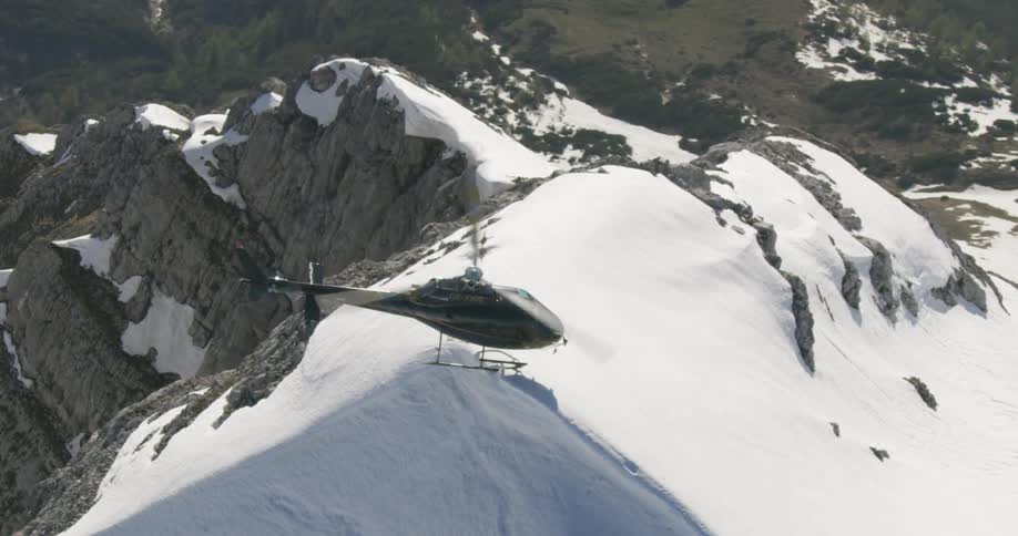 A helicopter hovering over a snowy mountain ridge