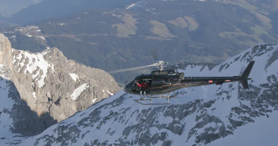 A helicopter flying overa snowy mountain ridge