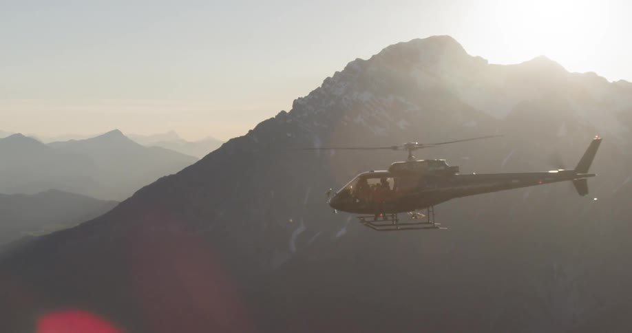 A helicopter flying through the mountains during the day