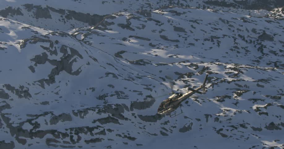 A helicopter flying above snowy mountain