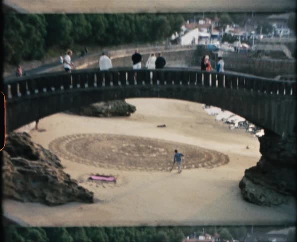 Tourists walk on a bridge over a park