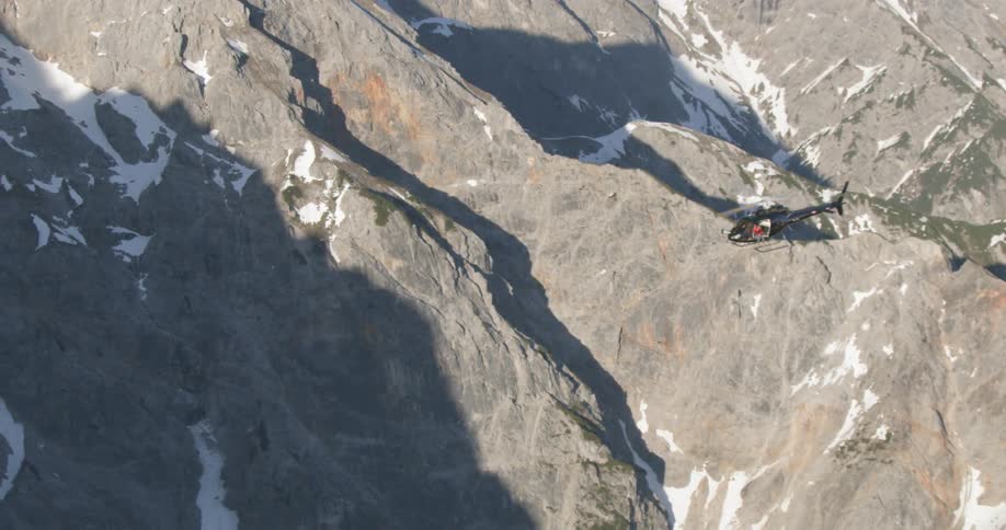 A helicopter flies over a snow covered mountain range
