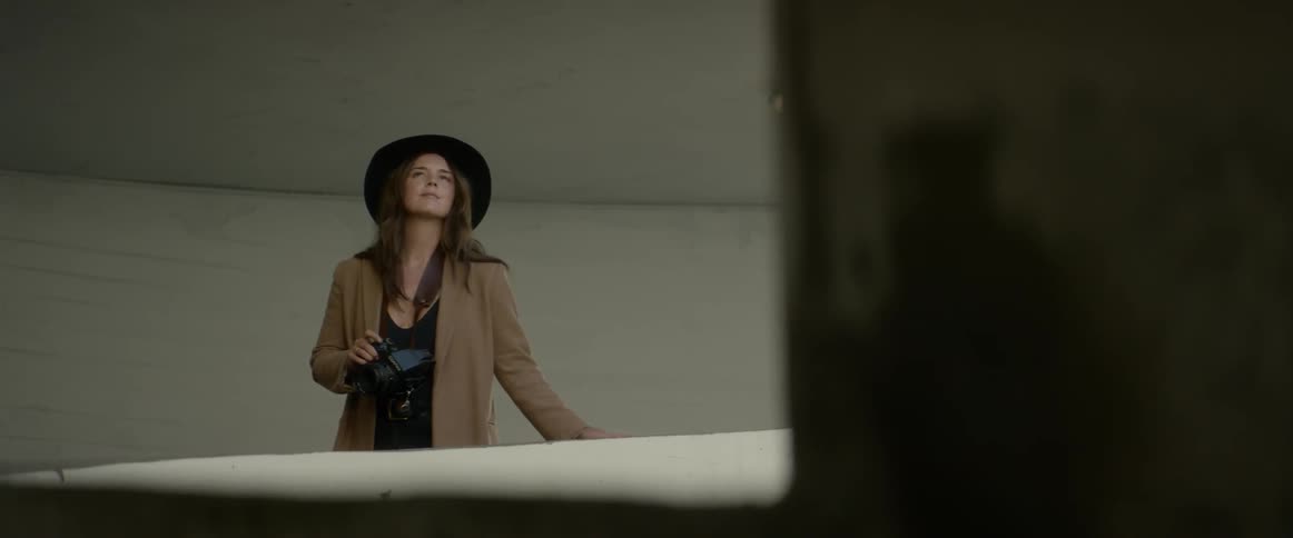 Woman wearing wide hat takes a picture with the camera during daylight