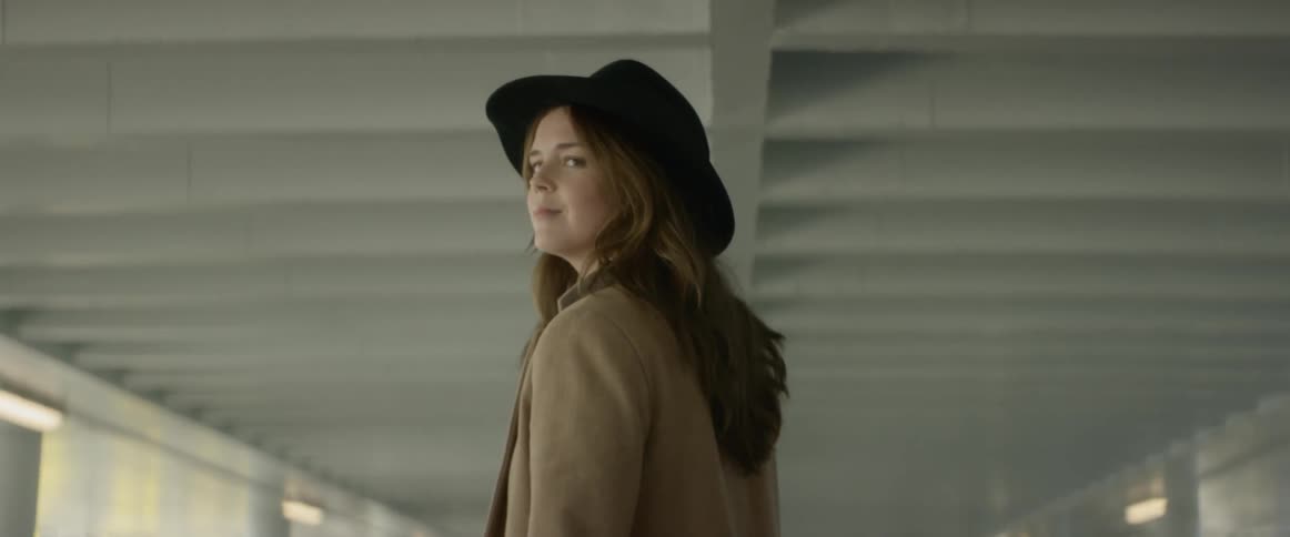 A woman is walking outdoors wearing a hat