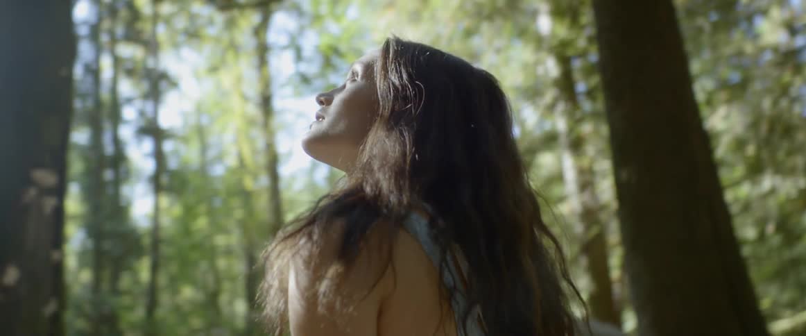 Woman looks up around in the woods during daylight