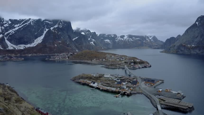 A bridge connecting two islands to the mainland with mountains and the sky in the background