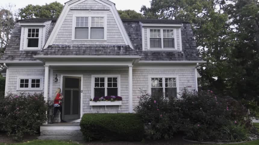 A woman walks up to the door of a home on a cloudy day