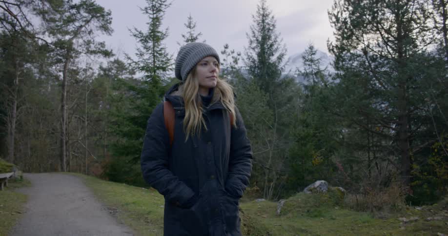 A woman is hiking on a trail by the woods
