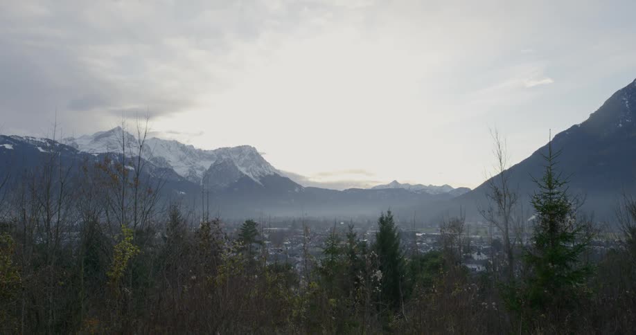 Forest trees with snow dusted mountain ridges on a cloudy day
