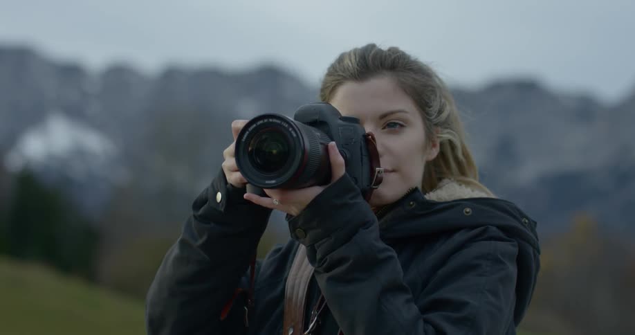 A woman holds up a professional camera to her face