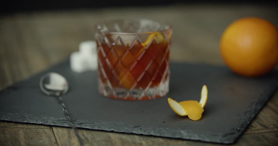 A drink with decorated with orange slices and peel lays on a placemat