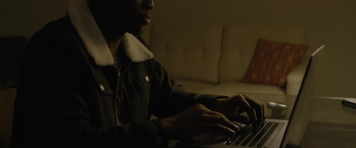 A black man types on a laptop computer
