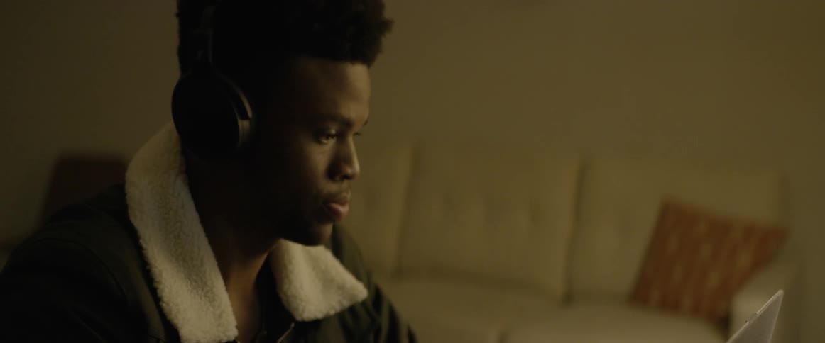 A man working on a laptop wearing headphones in the living room