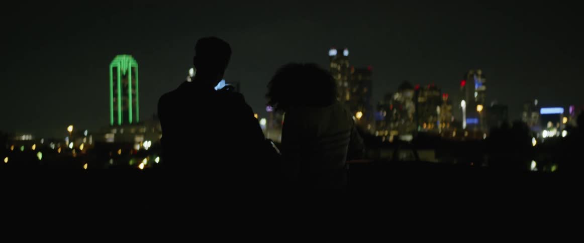 Silhouette of couple at night with bright city lights in background
