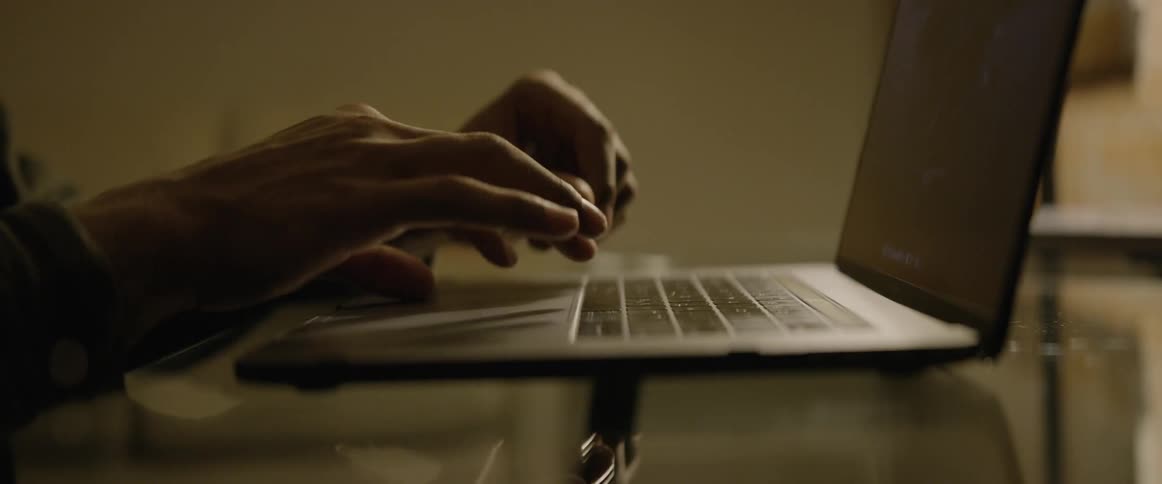 A black man types on a laptop computer