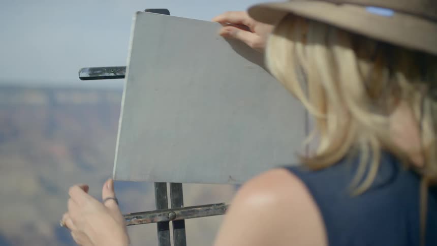 A woman puts a small canvas on her easel