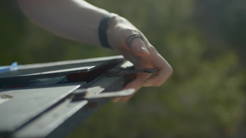 A woman holds an easel in her hands and then sets it up