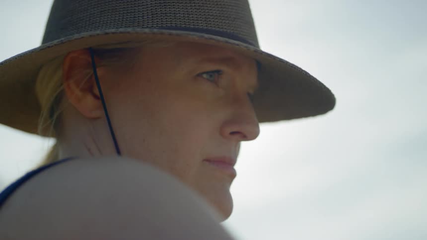 Blonde woman wearing wide hat looks around on a sunny day