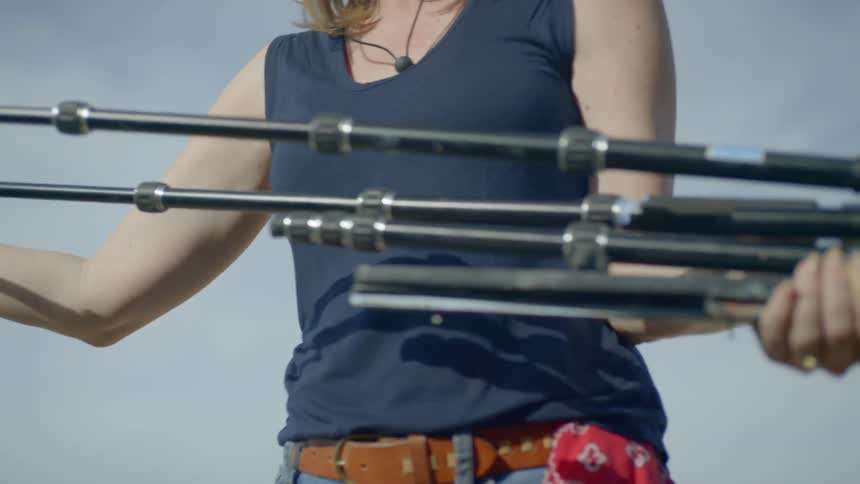 A woman pulls out the legs of a tripod