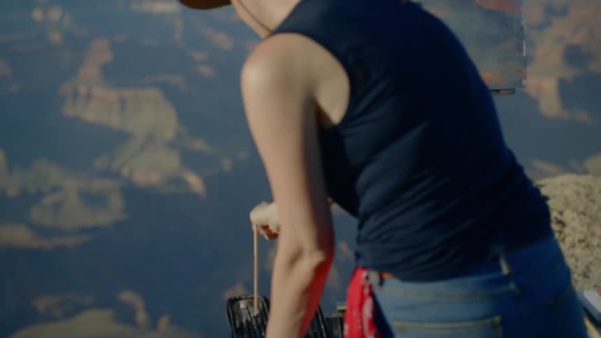 A woman grabs some paint brushes