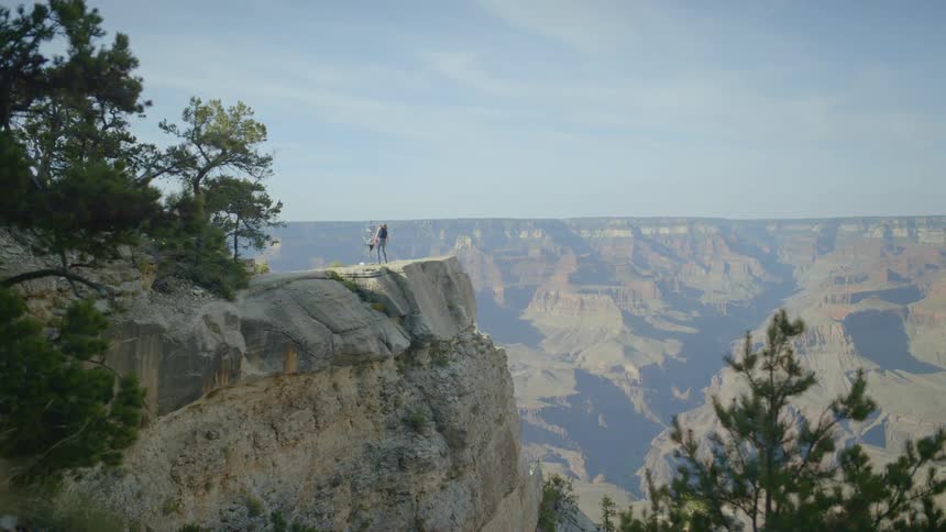 A person stands on the edge of a deep canyon