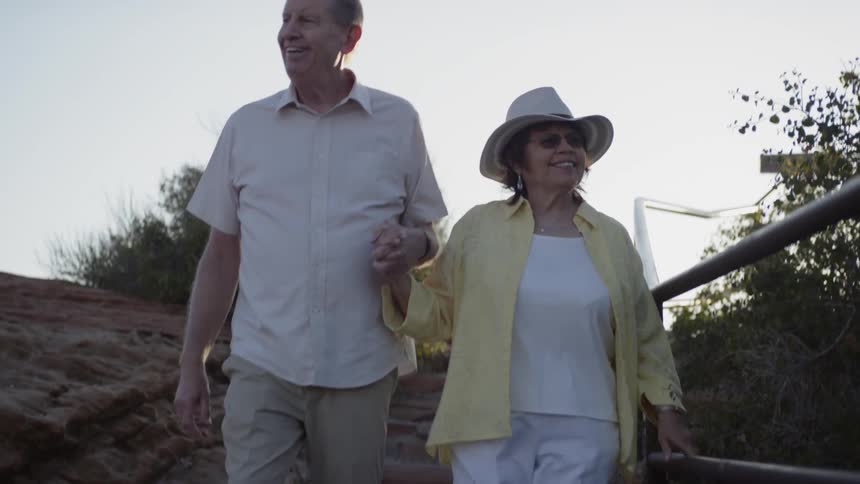 An elderly couple walks down a path