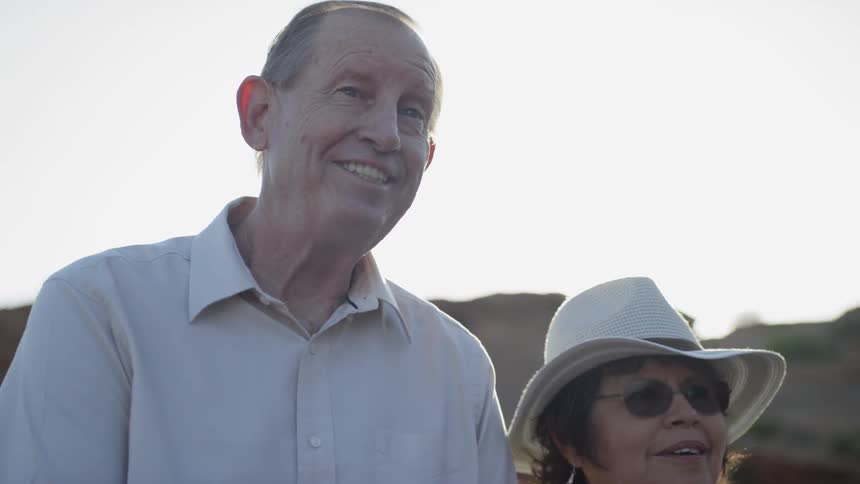 A man and a woman hold hands while standing under the sun