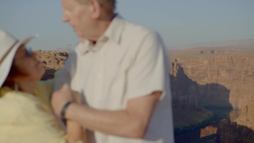 An elderly couple dances next to a canyon