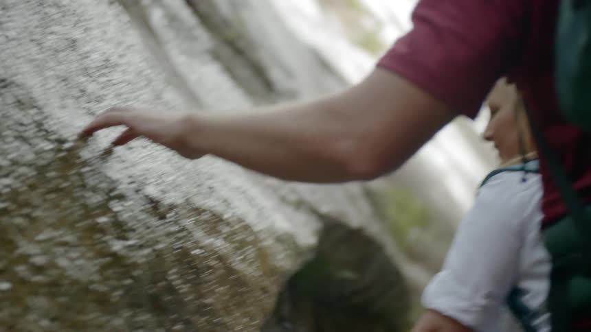 A group of people touch the rock formation while hiking