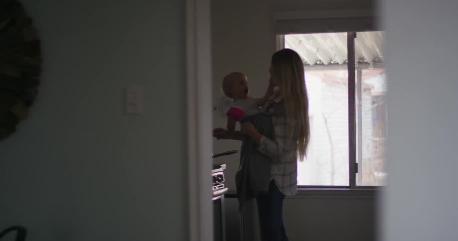 A woman holds a baby in the kitchen