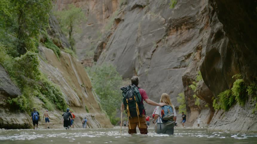 People wading through water as they hike in the wilderness