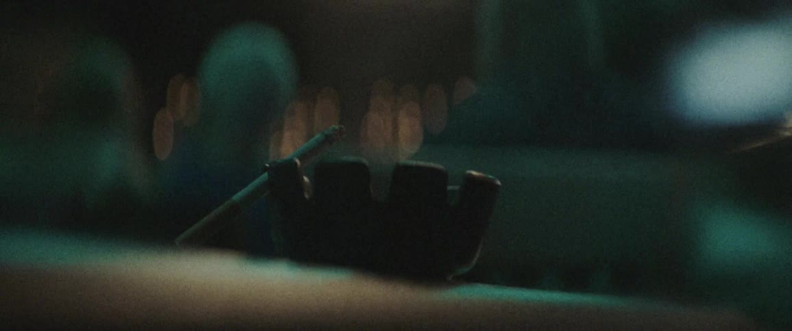 A cigarette burns in a black ashtray