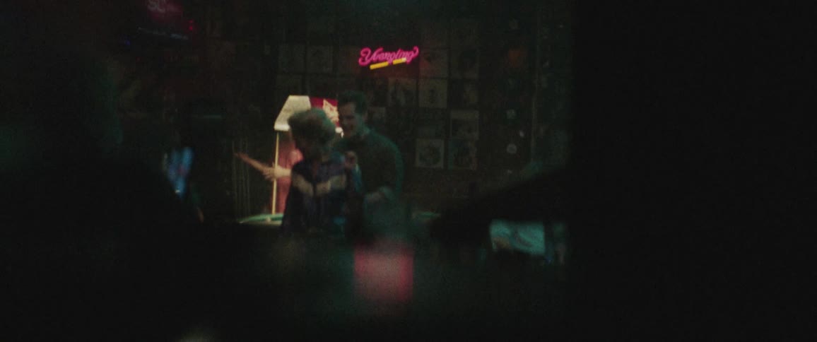 A man and woman dance together beside a pool table in a bar