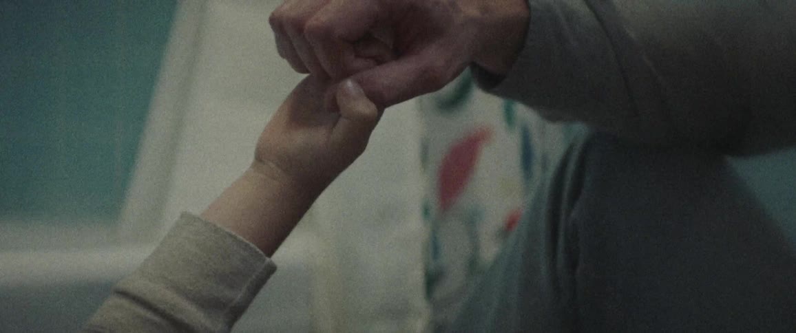 A child playing with the thumb of an older person holding their hand