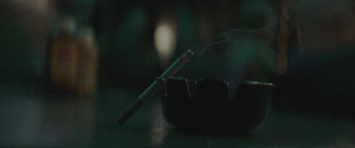 A lit cigarette leaned upon an ashtray on a table