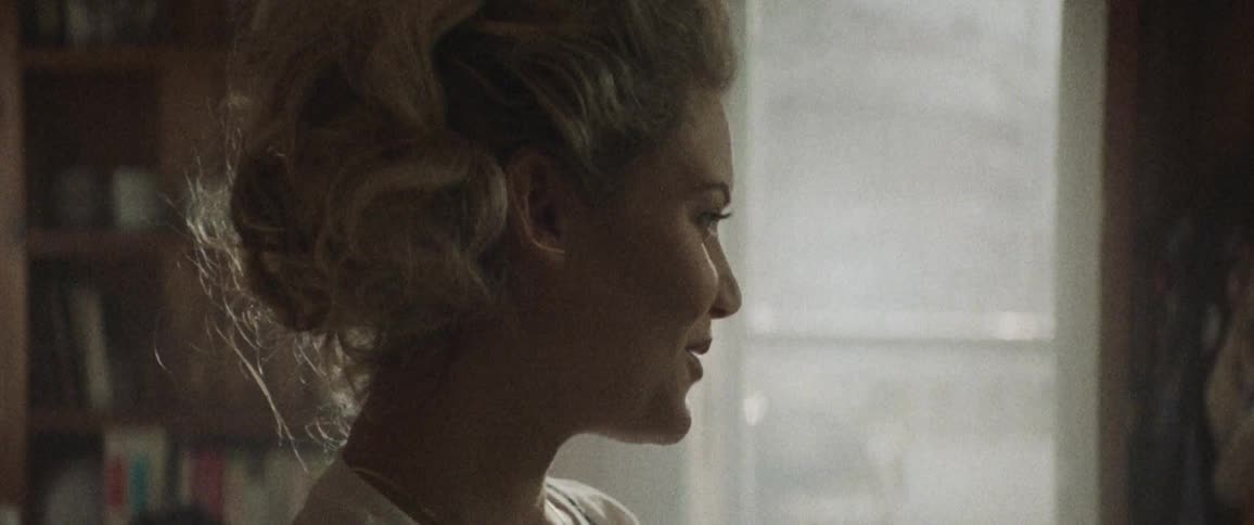 Blonde woman smiles and talks in a room during daylight