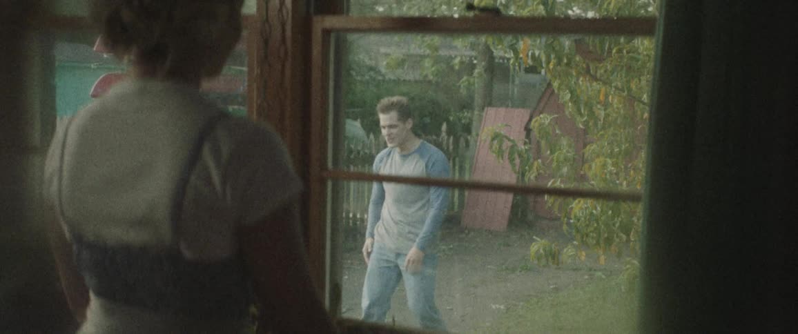 A woman watches a man and boy play in the backyard together