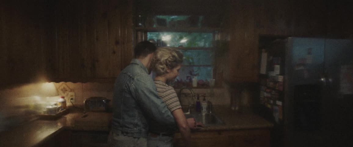 A man entering a kitchen and embracing a woman from behind